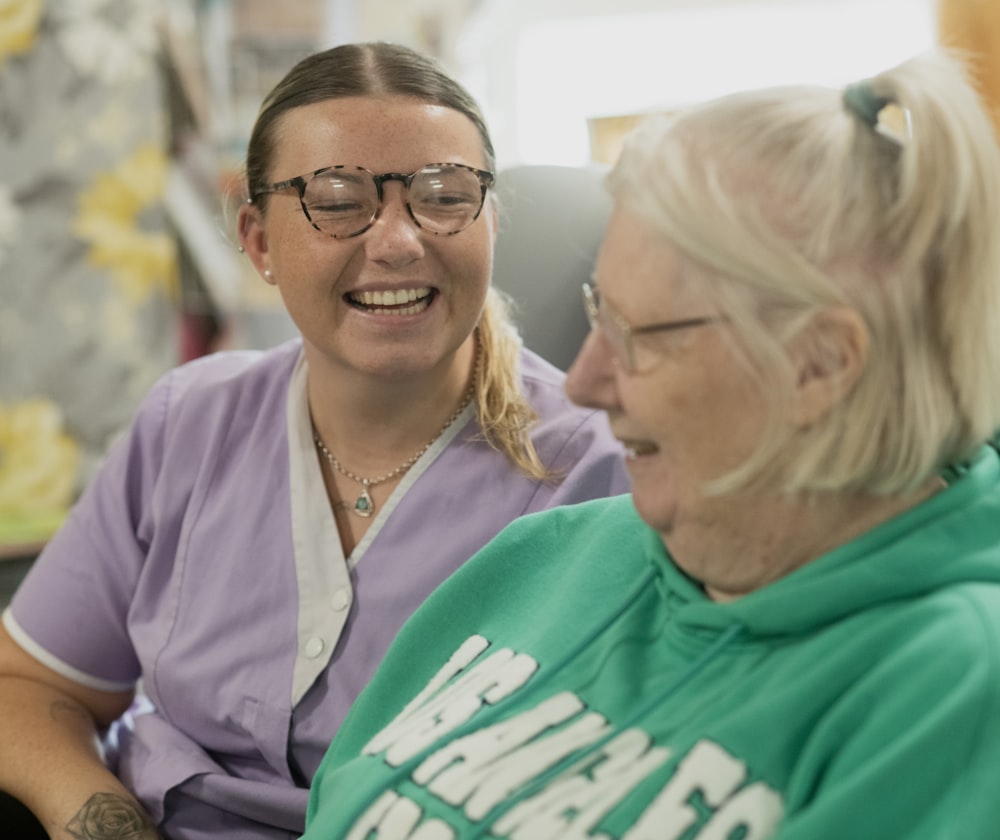 A support worker and an older woman laughing together